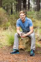 Handsome man sitting on a stone holding a water bottle
