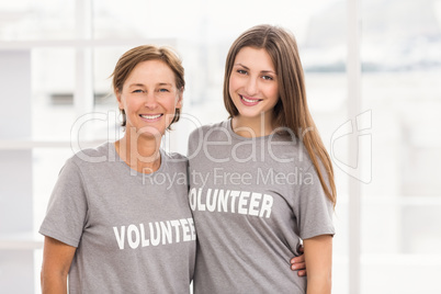 Smiling female volunteers putting arms around each other