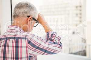 Troubled casual businessman leaning against window