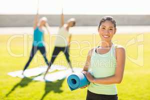 Smiling sporty woman in front of friends doing exercises