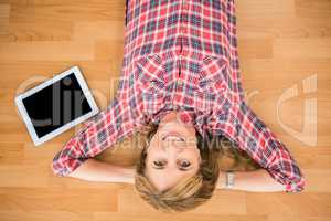 Smiling woman lying on floor next to tablet