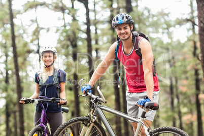 Young happy couple on bikes looking at camera