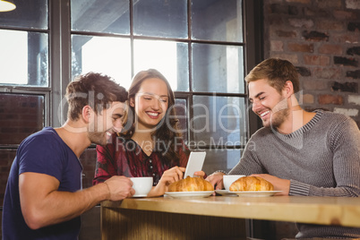 Smiling friends enjoying coffee and croissants together