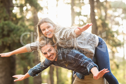 Smiling handsome man giving piggy back to his girlfriend