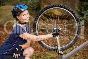 Smiling athletic blonde checking her mountain bike