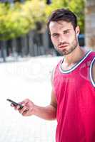 Handsome athlete sending a text
