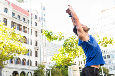 Handsome athlete stretching in front of buildings