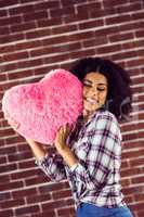 Attractive young woman cuddling with heart-shaped pillow