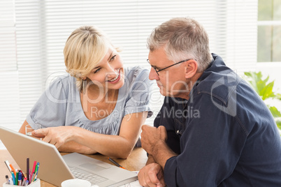 Smiling business team working together on laptop