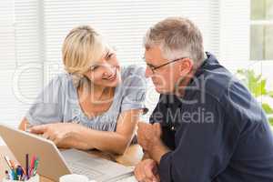 Smiling business team working together on laptop