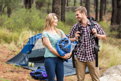 Young pretty hiker couple holding a sleeping bag and backpack