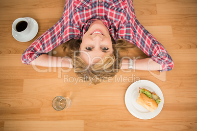 Smiling woman lying on floor surrounded by food and drink