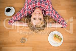 Smiling woman lying on floor surrounded by food and drink