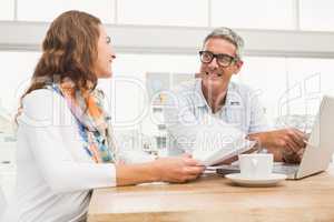 Two smiling casual designers working with laptop