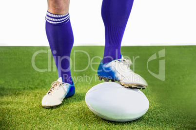 Rugby player posing feet on the ball