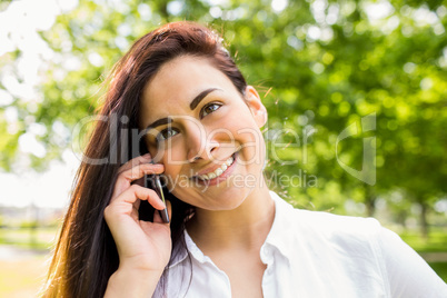 Beautiful brunette in the park making a call