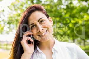 Beautiful brunette in the park making a call