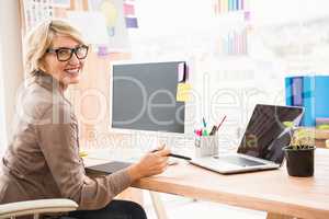 Smiling casual designer working at her desk