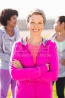 Smiling sporty woman with arms crossed in front of friends