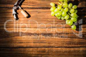 Grapes and corkscrew on table