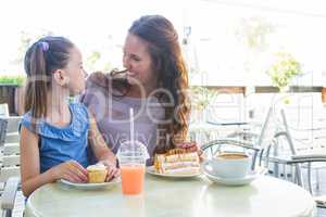 Mother and daughter enjoying cakes at cafe terrace