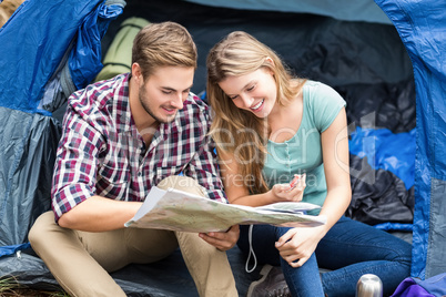 Young pretty hiker couple sitting in a tent looking at map