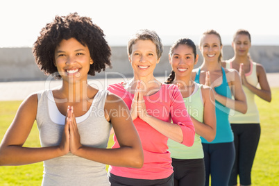 Smiling sporty women doing prayer position in yoga class