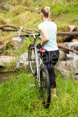 Rear view of a fit woman rolling her bike