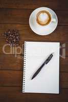 Cup of cappuccino and notepad with pen