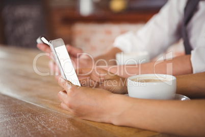 Cute couple sitting in cafe looking at smartphone