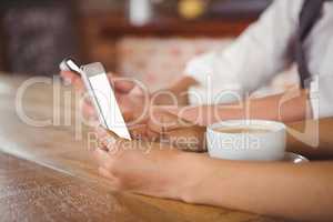 Cute couple sitting in cafe looking at smartphone