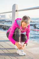 Sporty woman tying her shoelace at promenade