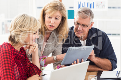 Smiling business team discussing over a tablet