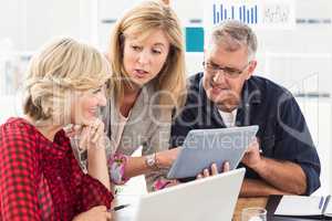 Smiling business team discussing over a tablet