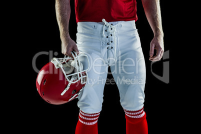 Front view of American football player holding his helmet