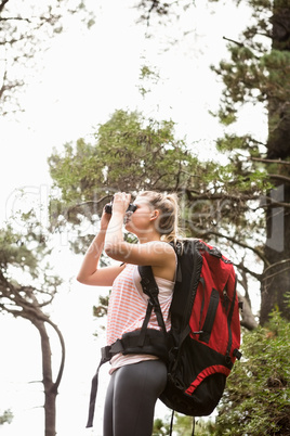 Blonde hiker looking through binoculars
