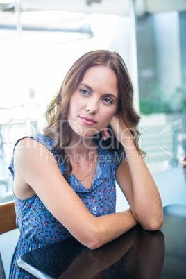 Pretty brunette thinking at table