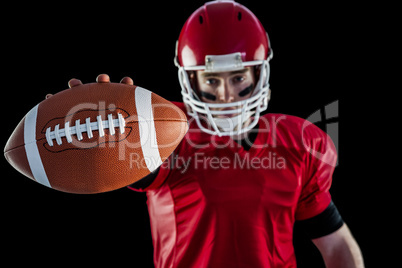 Portrait of american football player showing football to camera