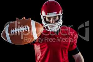 Portrait of american football player showing football to camera