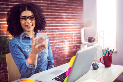 Casual businesswoman using her smartphone and smiling at camera