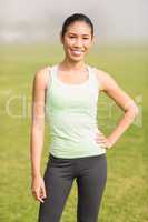 Smiling sporty woman with hand on hip