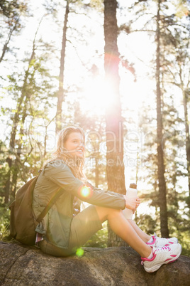 Pretty blonde hiker sitting on stone