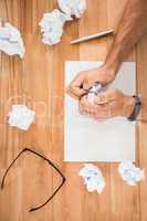 Hands crumpling paper on wooden desk