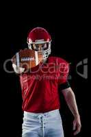 Portrait of american football player showing football to camera