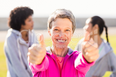 Sporty woman doing thumbs up in front of friends