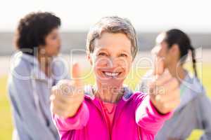 Sporty woman doing thumbs up in front of friends