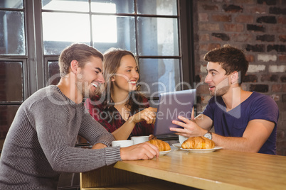 Smiling friends pointing and looking at tablet