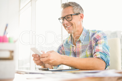 Smiling casual designer using smartphone