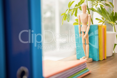 Mannequin and stack of books on wooden window sill