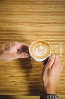 Hands holding cappuccino with coffee art